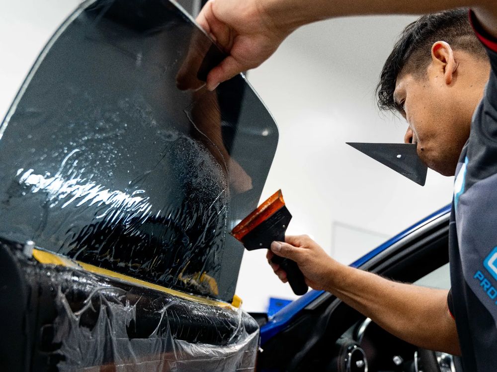 Technician fitting ceramic window tint to a rear window